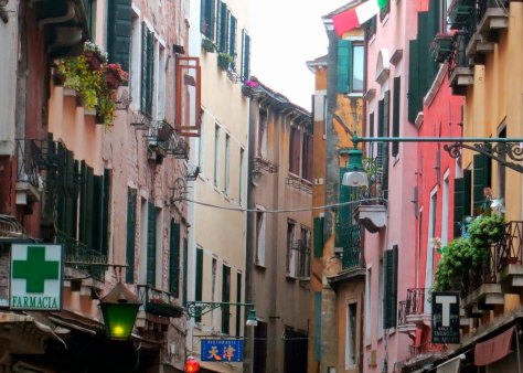 Venice street scene showing colorful buildings and flower boxes.