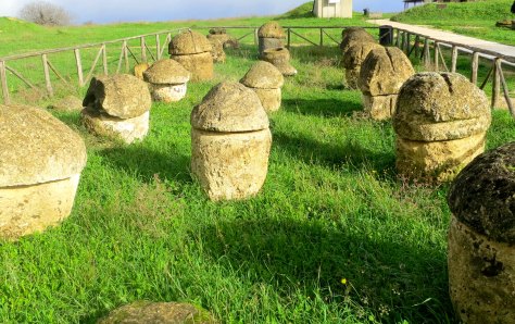 These funerary urns found in Tarquenia were used for cremated remains and buried in tombs. The contrast of the green grass, dark clouds and bright sun made a colorful photo.