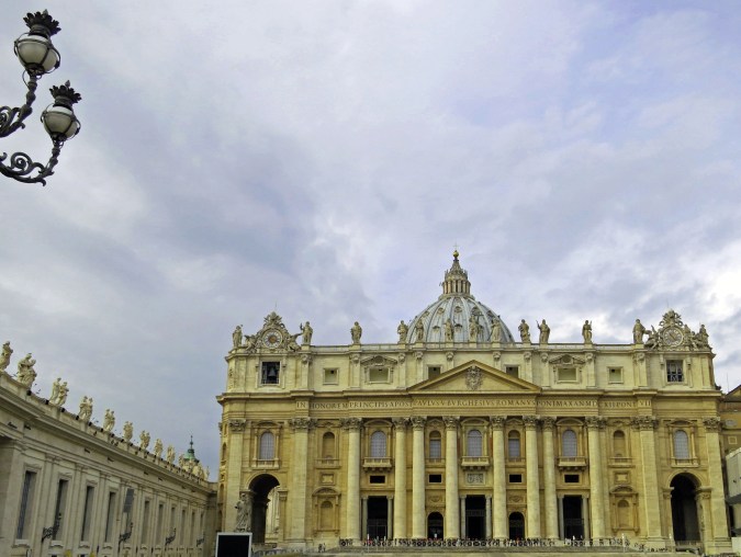 Cloudy skies provide a dramatic backdrop for St. Peter's Basilica with its magnificent dome designed by Michelangelo. 