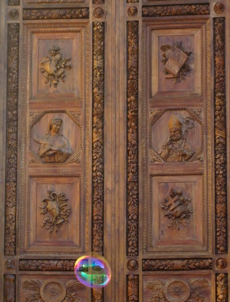 A huge soap bubble went floating up by the beautiful wooden doors of Santa Croce.