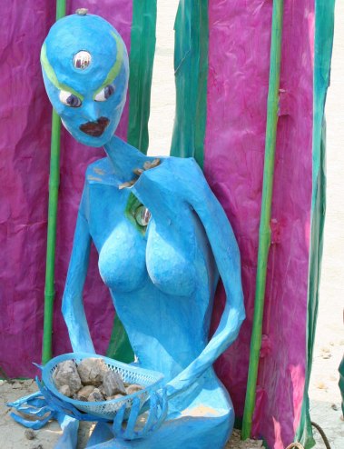 Blue alien woman at Burning Man 2013 with fine collection of rocks.
