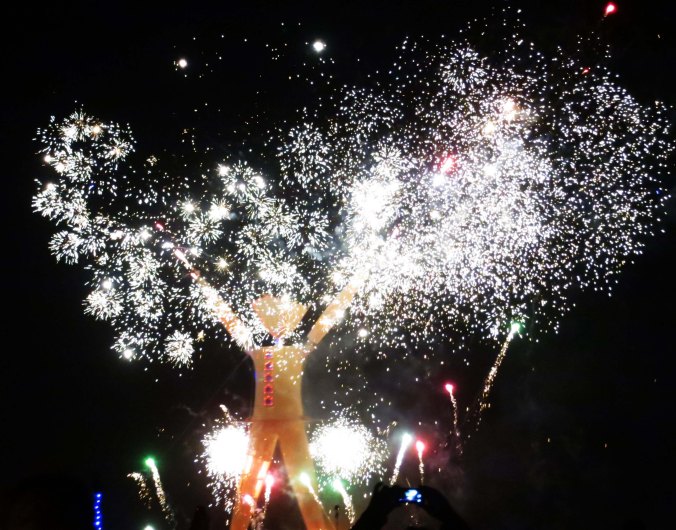 The night sky is lit up by fireworks during the burning of the Man at Burning Man 2014.