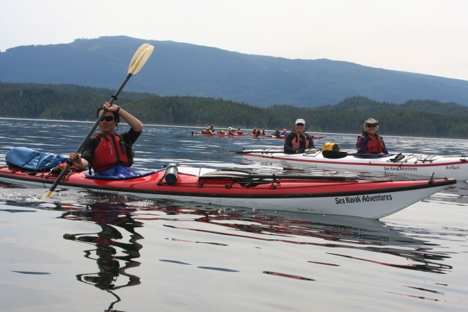 I liked the watch the waves distorted the reflection of Quy in the water. Edie and Dave look on. The other kayakers are watching the approach of a cruise ship. (Photo by Peggy Mekemson.)