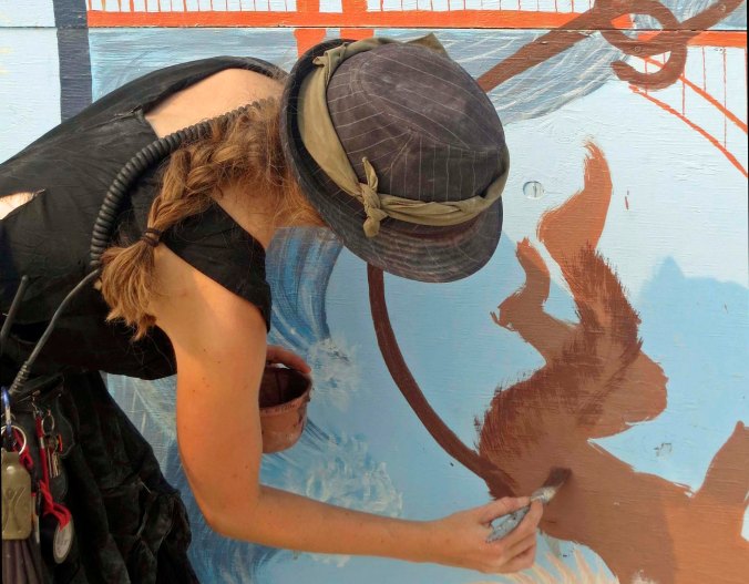 A mural artist at work painting a monkey.