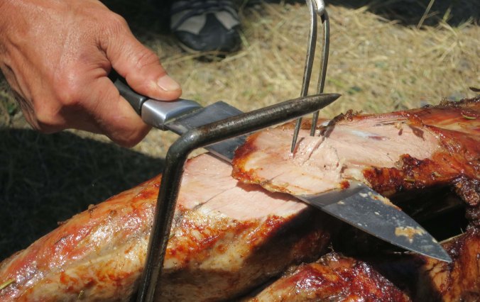 Brian carves meat off the goat roast.