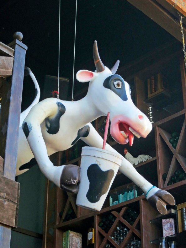 A flying cow serves as an enticement to one of the many bars.