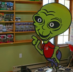 Alien points out brochures in Information Bureau in Moonbeam, Ontario Canada.