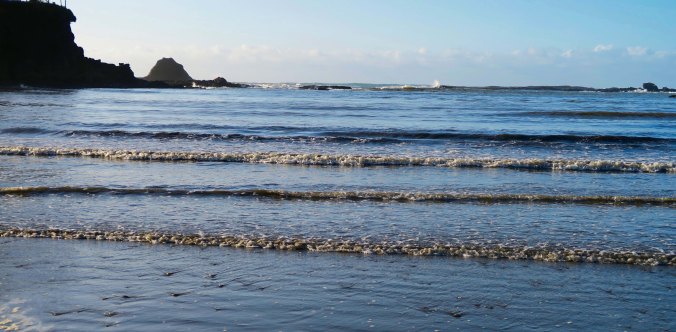 Sun lights up small waves at Sunset Bay on the Oregon Coast near Coos Bay.