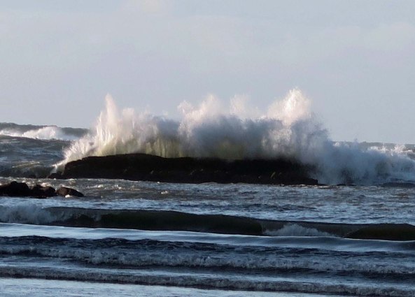 Backlit wave crashes over rock at Sunset bay near Coos Bay, Oregon.