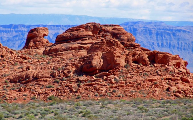 Distant mountains add contrast and depth to the bright red sandstone. (Photo by Peggy Mekemson.)