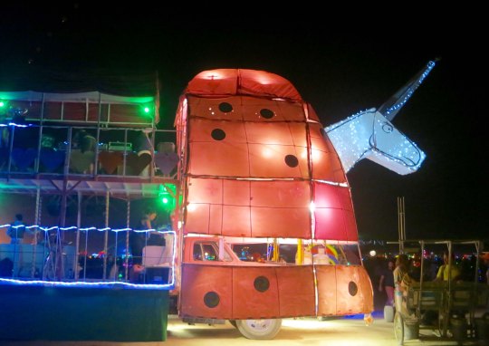 Large mutant vehicle unicorn at night at Burning Man.