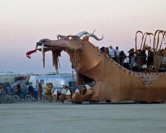 Golden dragon mutant vehicle at Burning Man with eyes glowing.