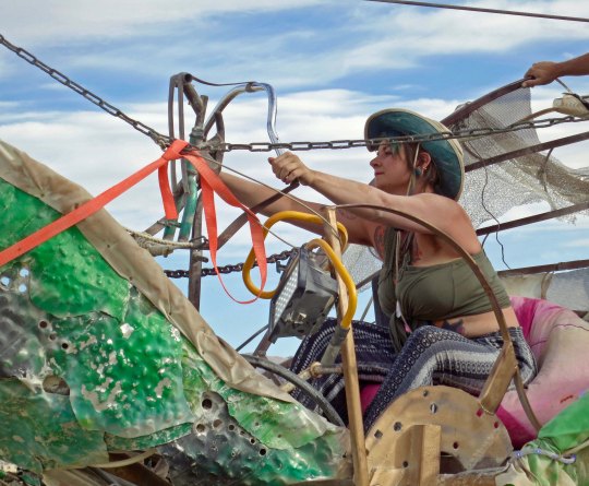 Burner uses cables to operate green mutant dragon at Burning Man.