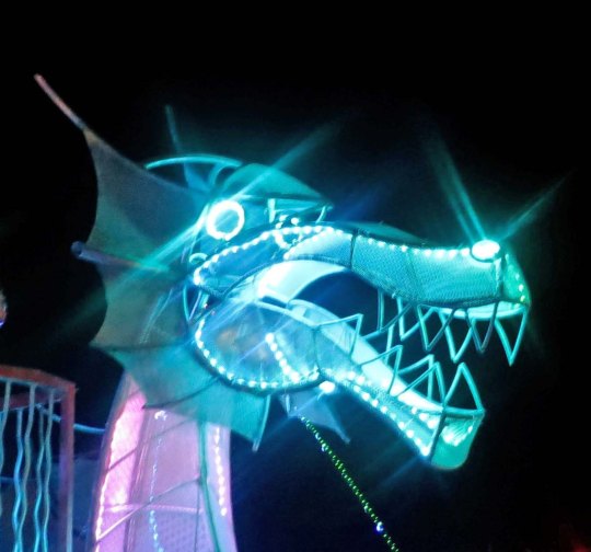 Striking green head of mutant vehicle dragon at night at Burning Man.